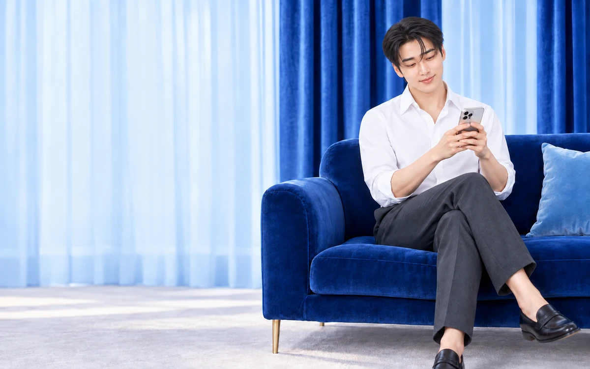 파란 소파에 앉아 휴대폰을 보는 머니콜 남성 모델